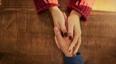 Cropped high angle shot of an unidentifiable man and woman holding hands on a table